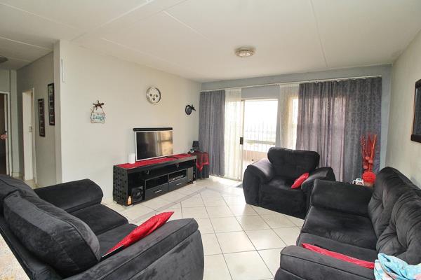 This spacious unit features an open-plan living area with tiled flooring, seamlessly ...