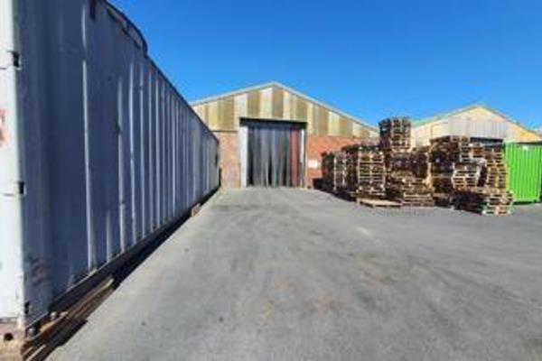 Two large, spacious warehouses are located within a secure, gated area. These warehouses ...