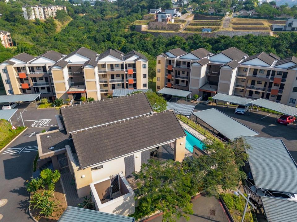 Close-up aerial view of the Westwood Terraces central amenity hub showing covered communal braai and entertainment lapa adjacent to a rectangular swimming pool, surrounded by residential blocks and covered parking.